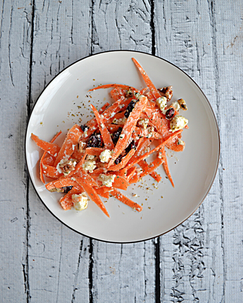 A plate filled with shredded carrots, craberries, and feta.