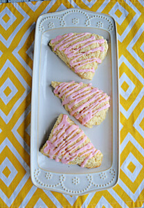A platter with three grapefruit scones drizzled with pink grapefruit glaze.