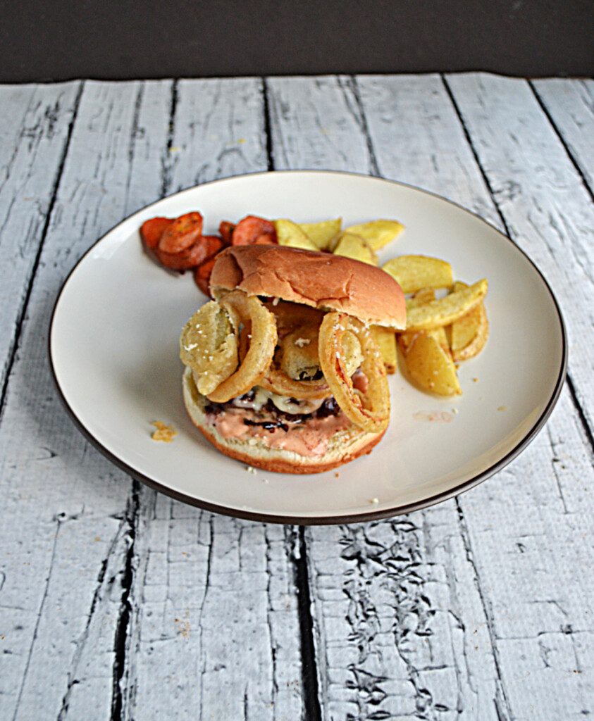 A burger topped with fried pickles and onions. 