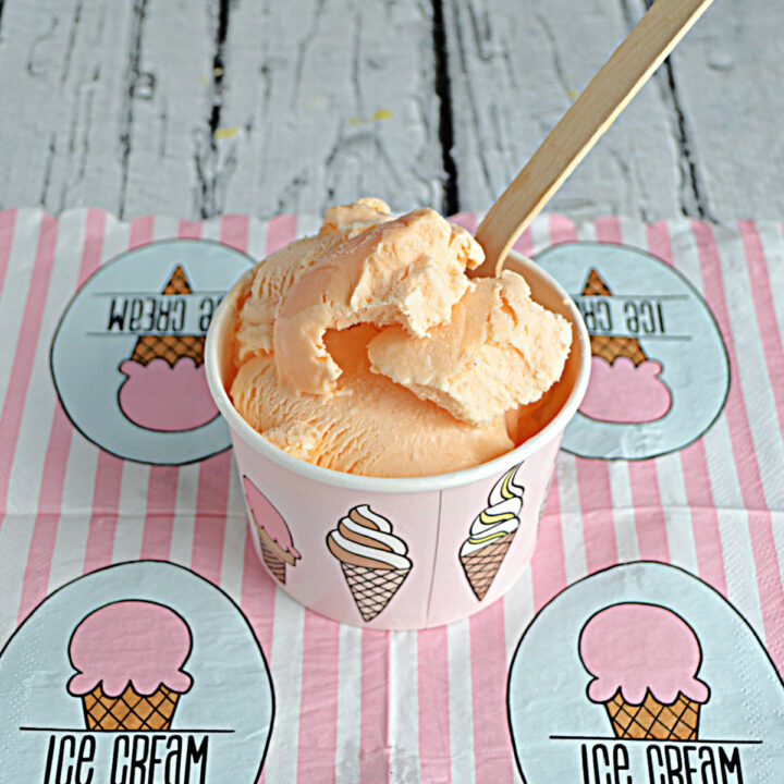 A pink and white ice cream napkin with a bowl of Thai Tea Ice Cream with a wooden spoon in it.