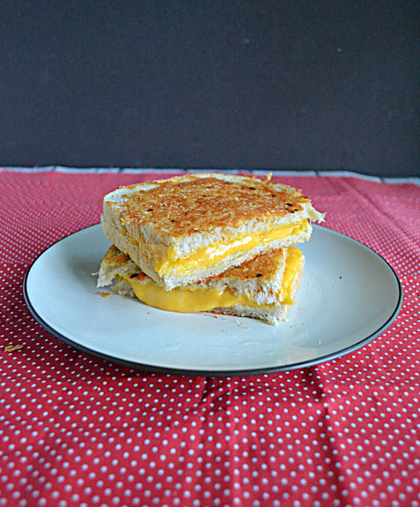 Front view of a grilled cheese, cut in half, on a plate, and stacked. 