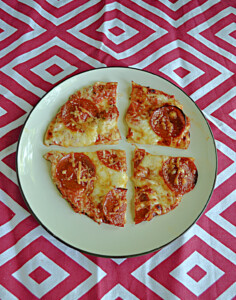 A plate with a pepperoni tortilla pizza cut into quarters.