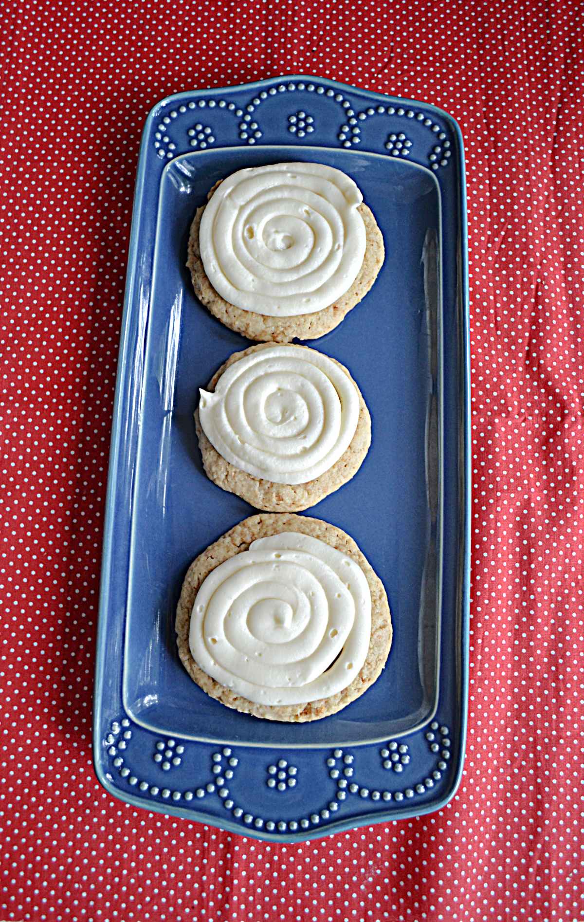A blue platter with three larger NY Cheesecake Cookies topped with cheesecake frosting.