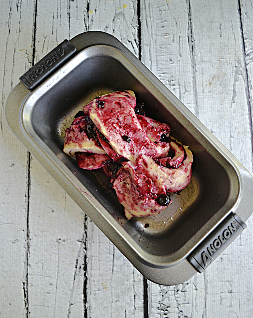 A baking pan with bread dough and blueberry jam in it.