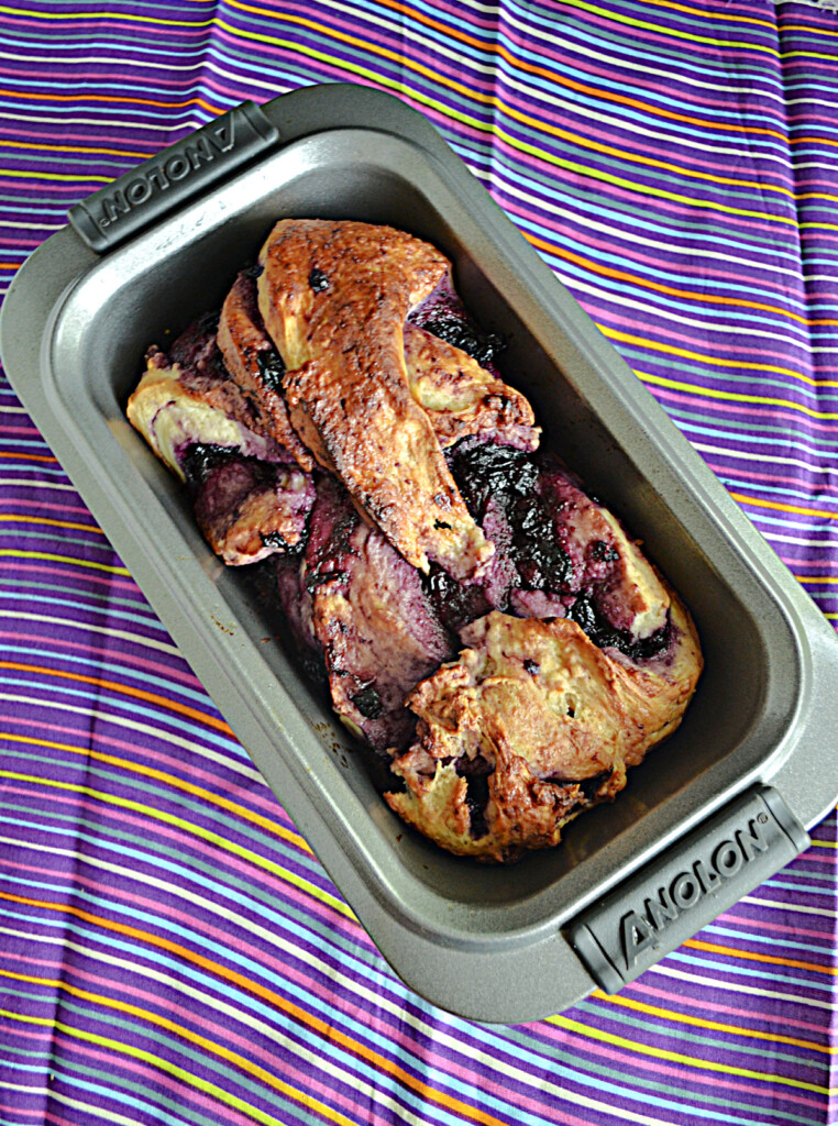 A baking pan with a loaf of bread and blueberries in it.