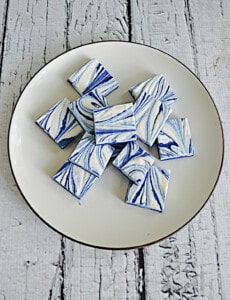 A plate with pieces of white and blue swirled fudge on it.
