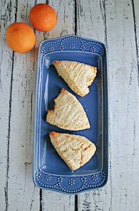 A platter with three orange scones on it.