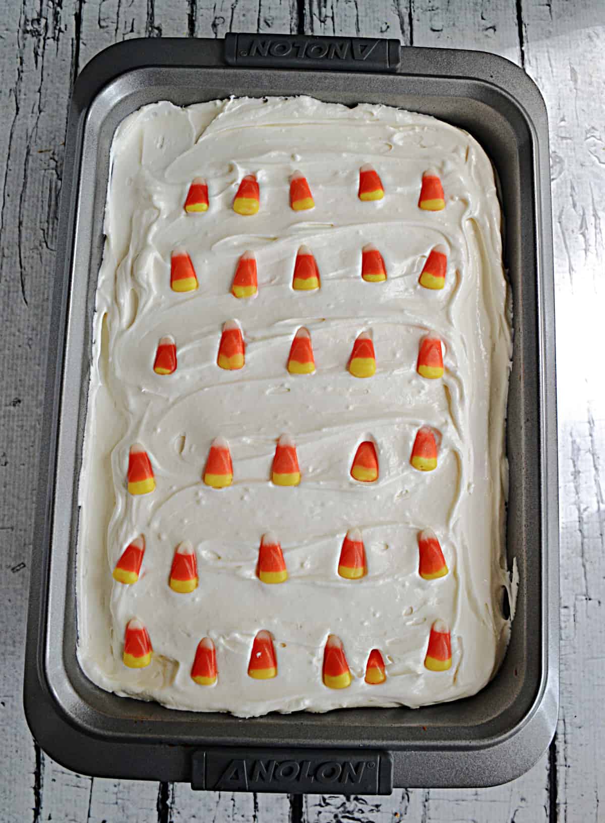 A cake with white frosting and candy corn on top.