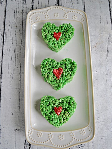 Three green heart shaped Rice Krispies Treats with a red heart in the middle.
