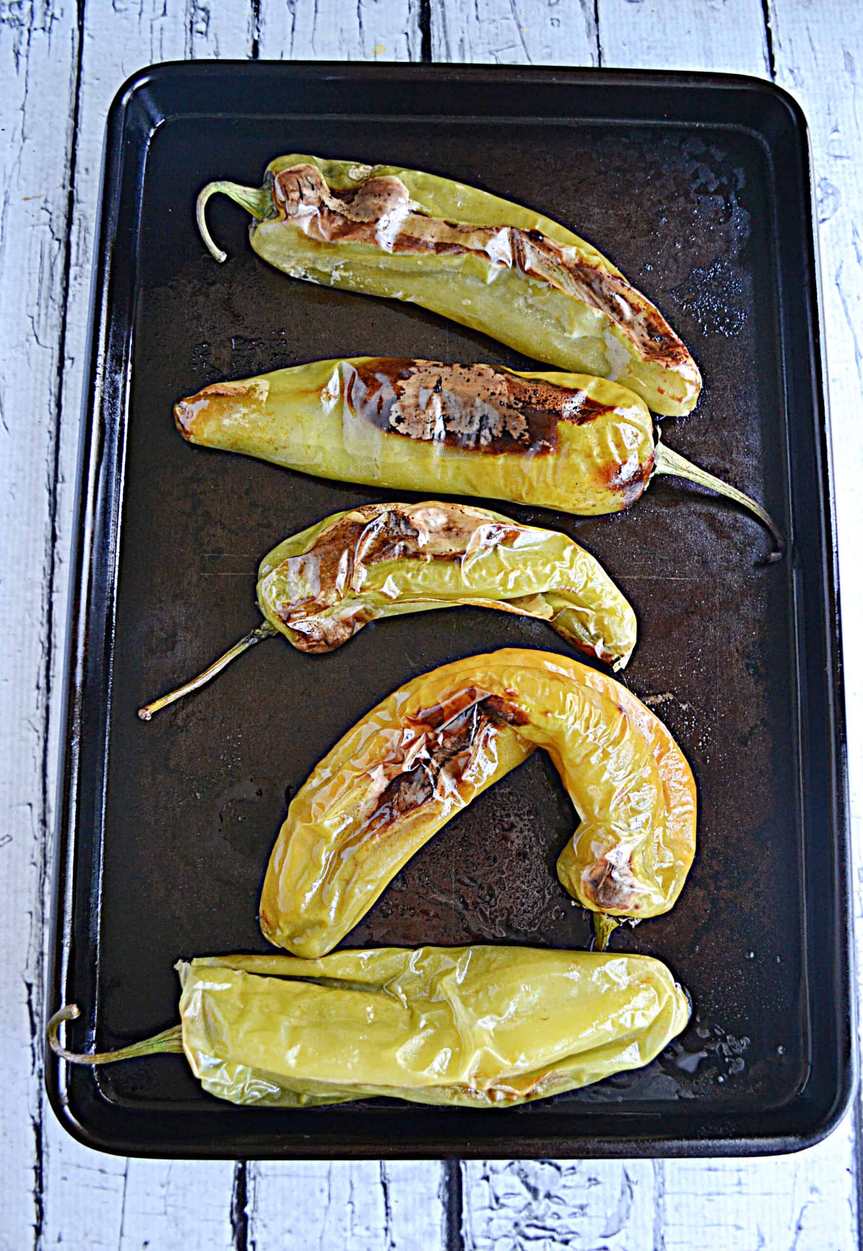 A baking sheet with roasted Hatch chiles on it.