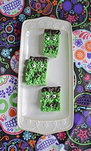 A platter with three green Frankenstein Rice Krispies Treats on it.