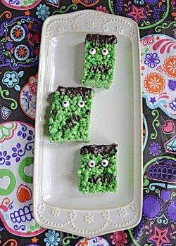 A platter with three green Frankenstein Rice Krispies Treats on it.