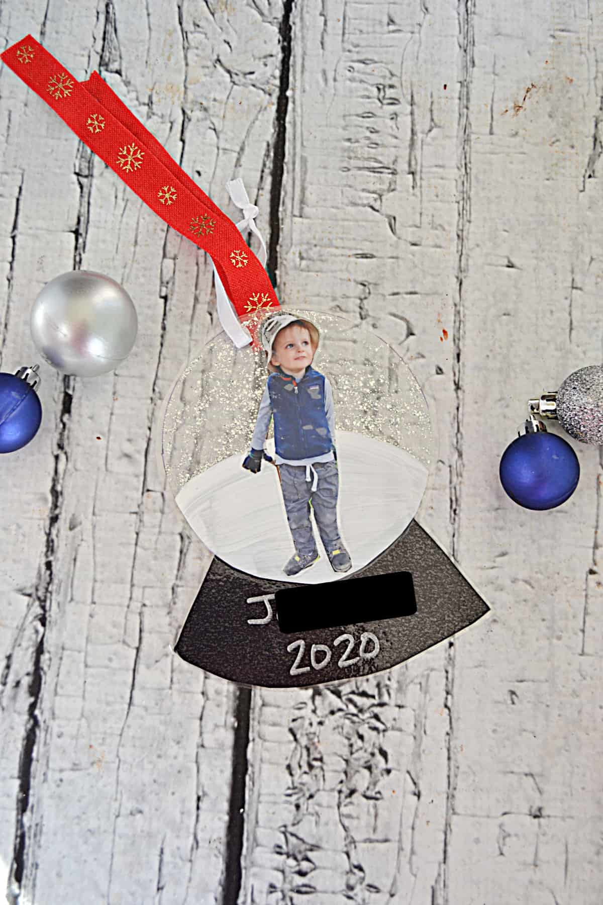 A DIY snowglobe ornament with a red ribbon hanger.
