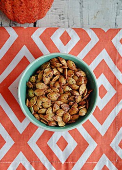 A close up view of a bowl of roasted pumpkin seeds.