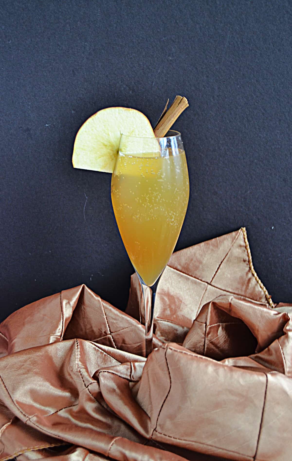 A close up view of an apple cider mimosa in a champagne glass.