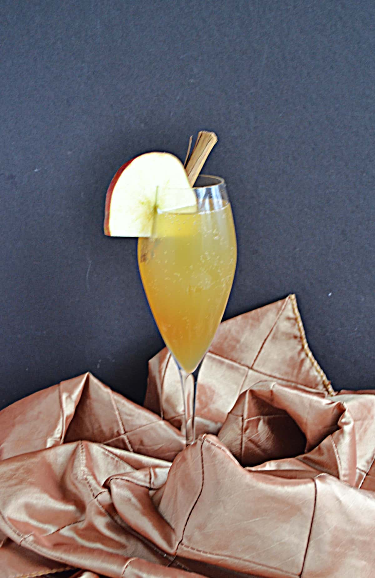 A glass with Apple Cider Mimosa and an apple wedge.
