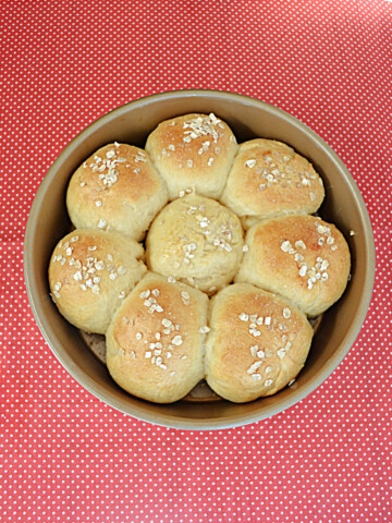 A round pan with 8 golden brown rolls in it.