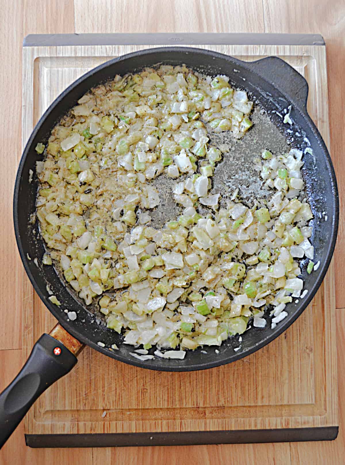 A skillet with celery and onions in it.