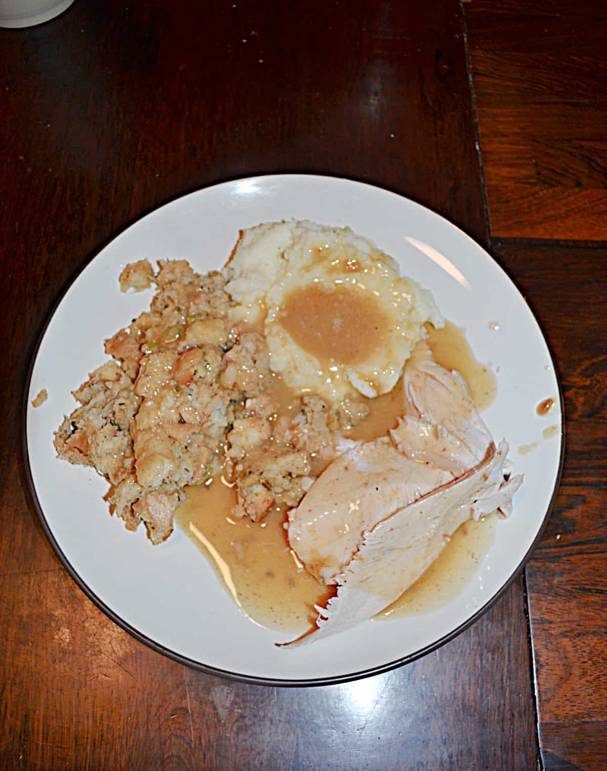 A plate with turkey, mashed potatoes, stuffing, and gravy on it.