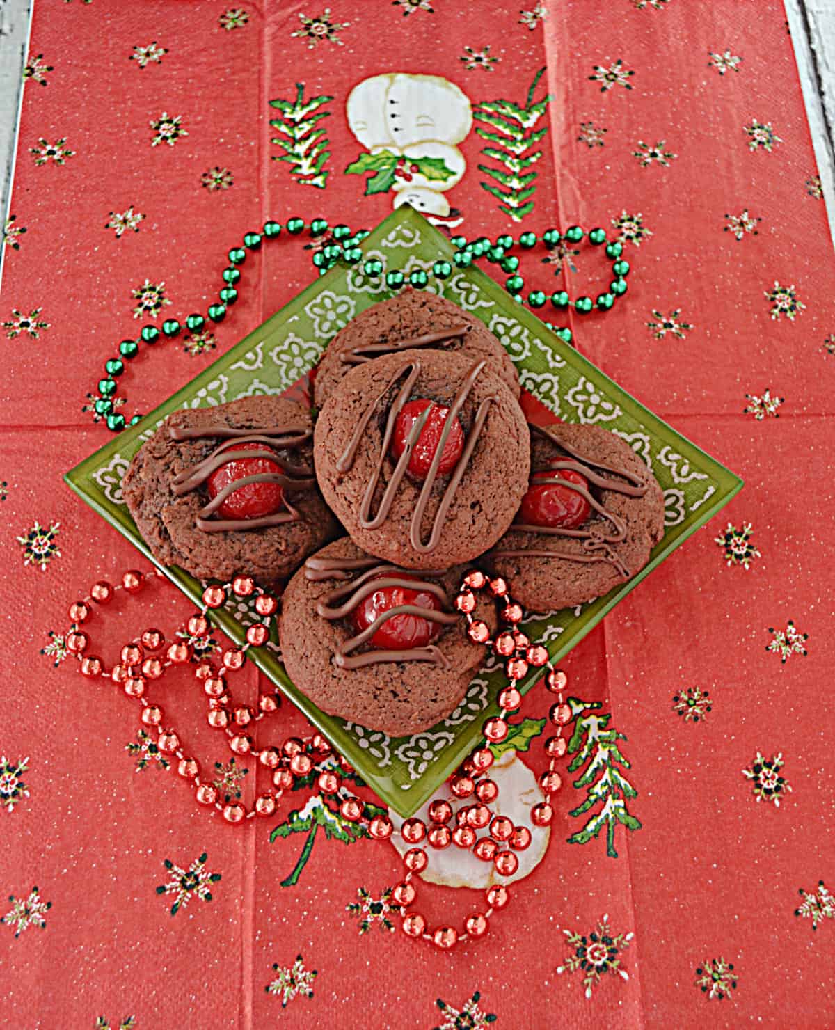 A small plate piled with chocolate covered cherry thumbprint cookies.