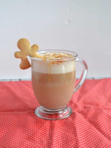 A mug of Gingerbread Latte with a cookie on the rim.