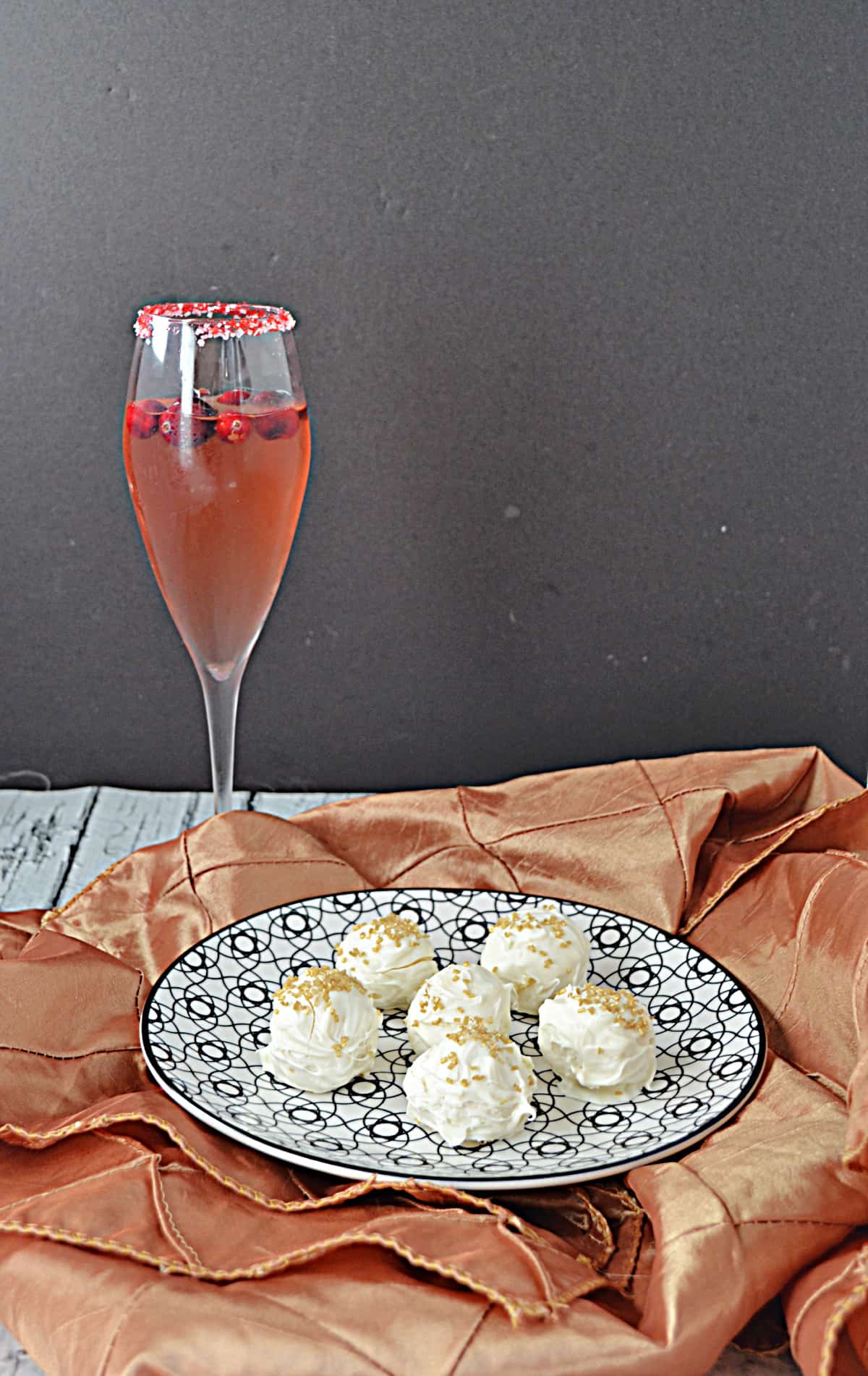 A plate of champagne truffles with a cranberry cocktail behind it.