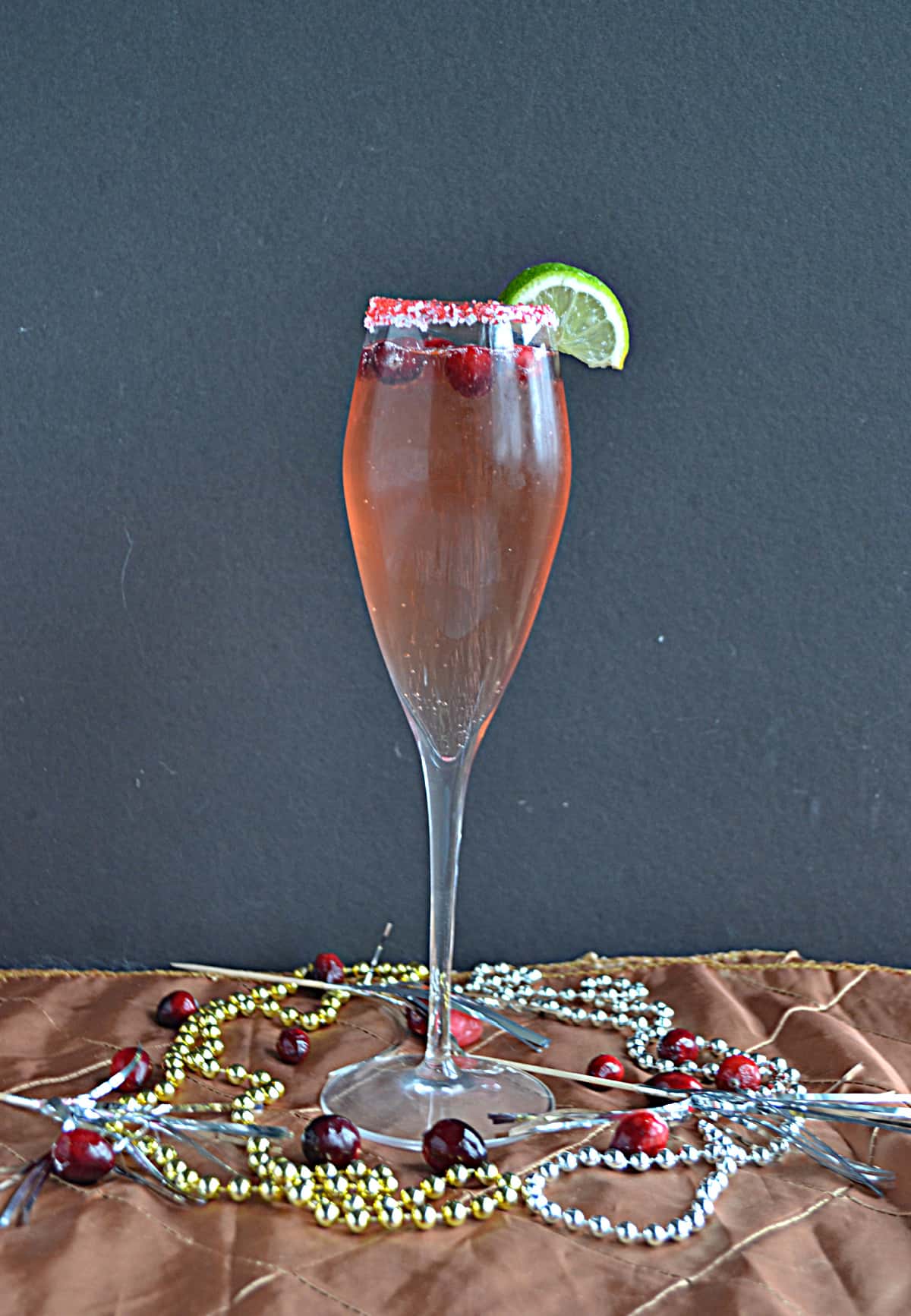 A glass of Cranberry Champagne Cocktail with beads around the base of the glass.