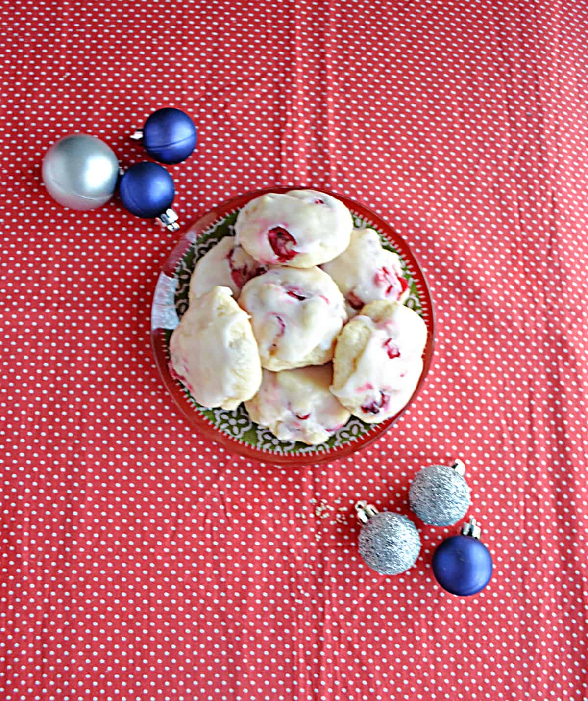 A top view of a plate of cranberry lemon cookies with ornaments around the plate. 