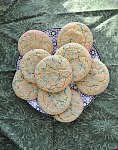 A plate of cookies with green and gold sprinkles on top.
