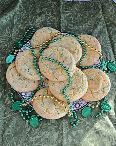 A plate of St. Patrick's Day cookies with green and gold beads on the plate.