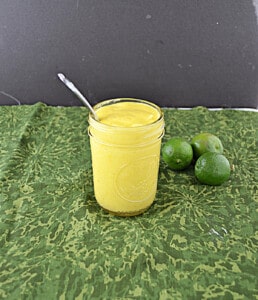 A jar of key lime curd with key limes beside it.