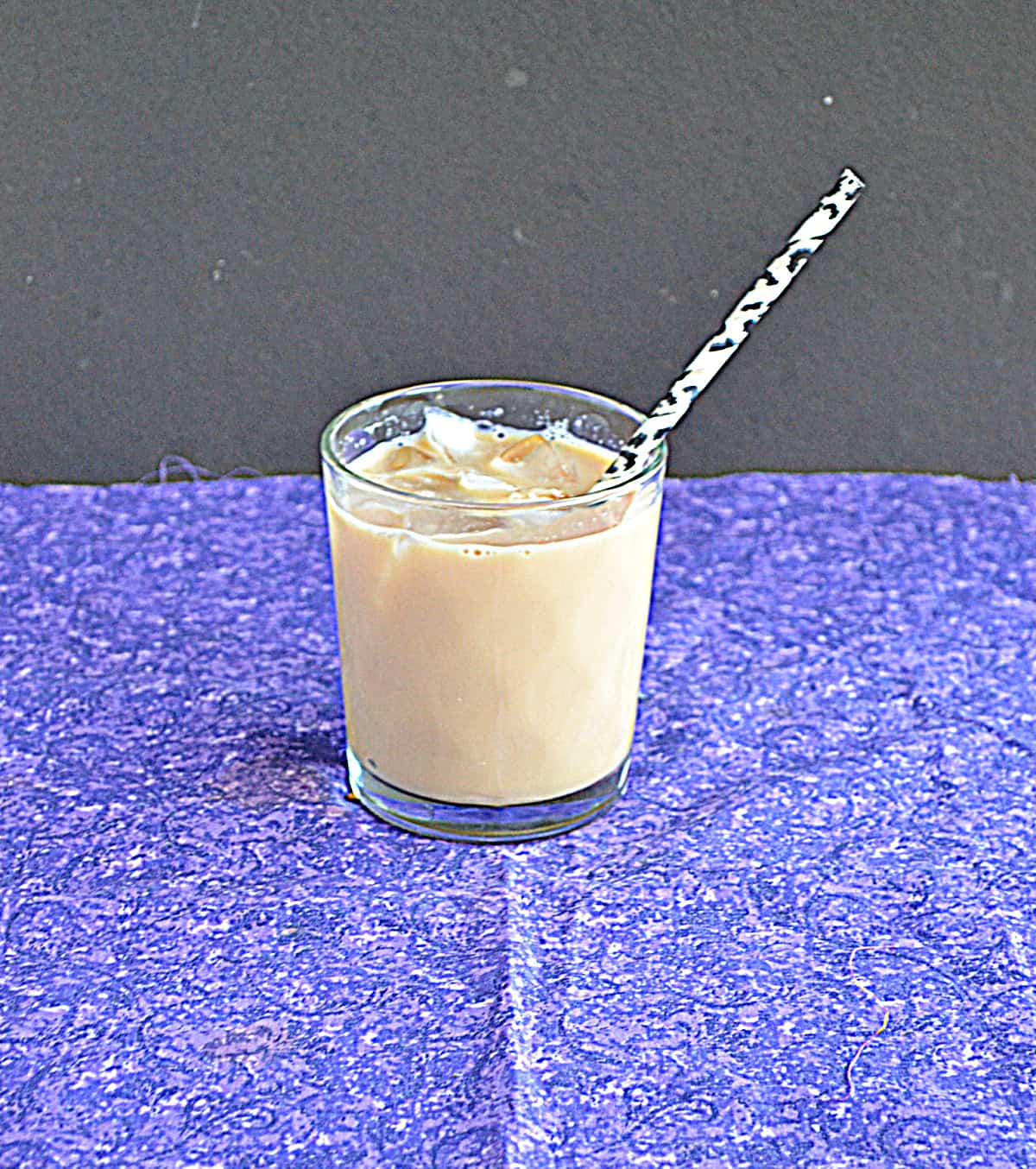A glass of iced tea latte over ice with a straw.