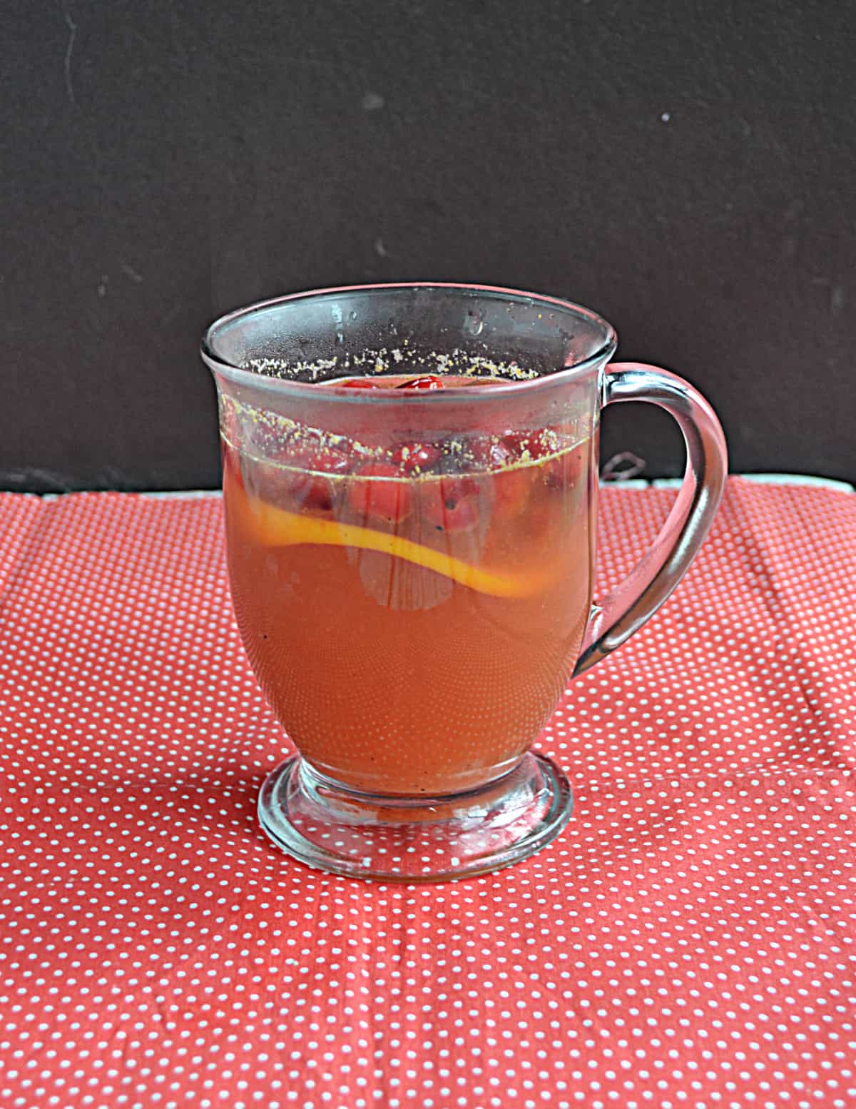 A mug of cider with orange slices in it.