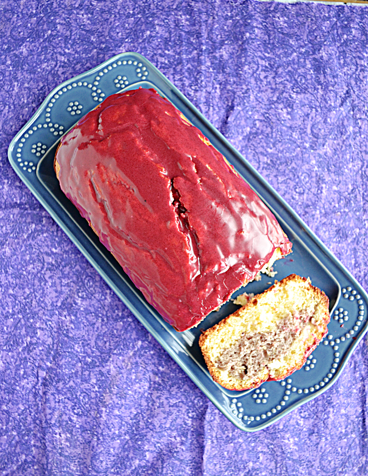 A loaf of HIbiscus cake with deep purple red glaze.