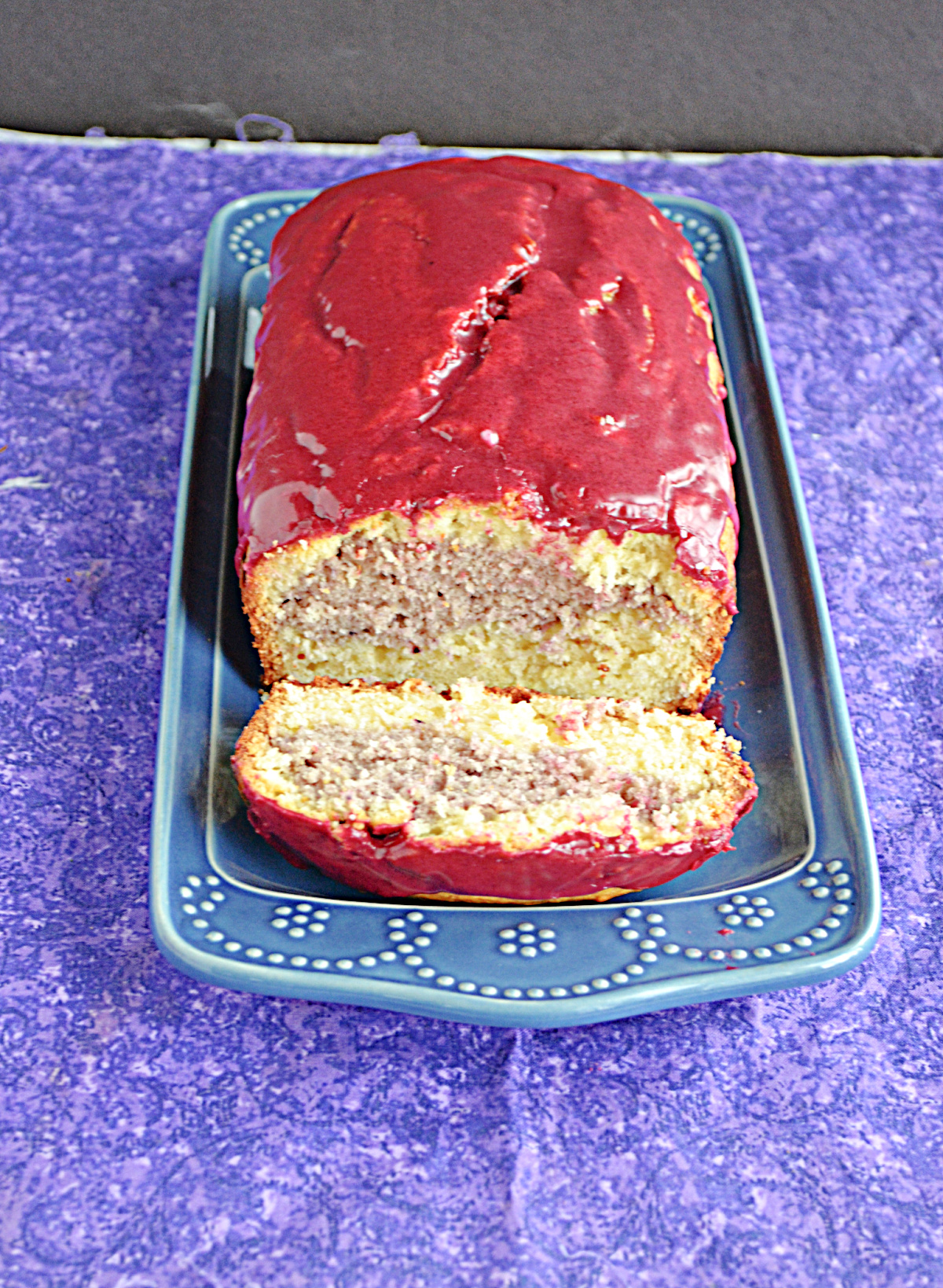 Close up view of the cut Hibiscus cake with the purple hibiscus stripe inside the almond cake. 