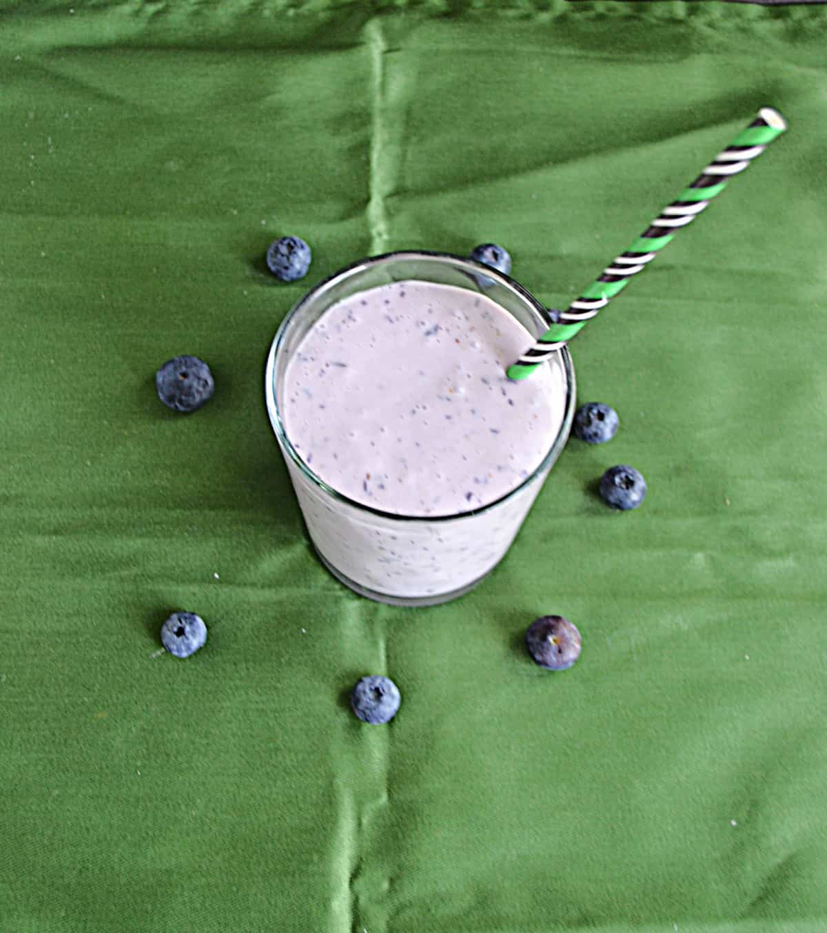 A top view of a blueberry banana smoothie with a straw in it.