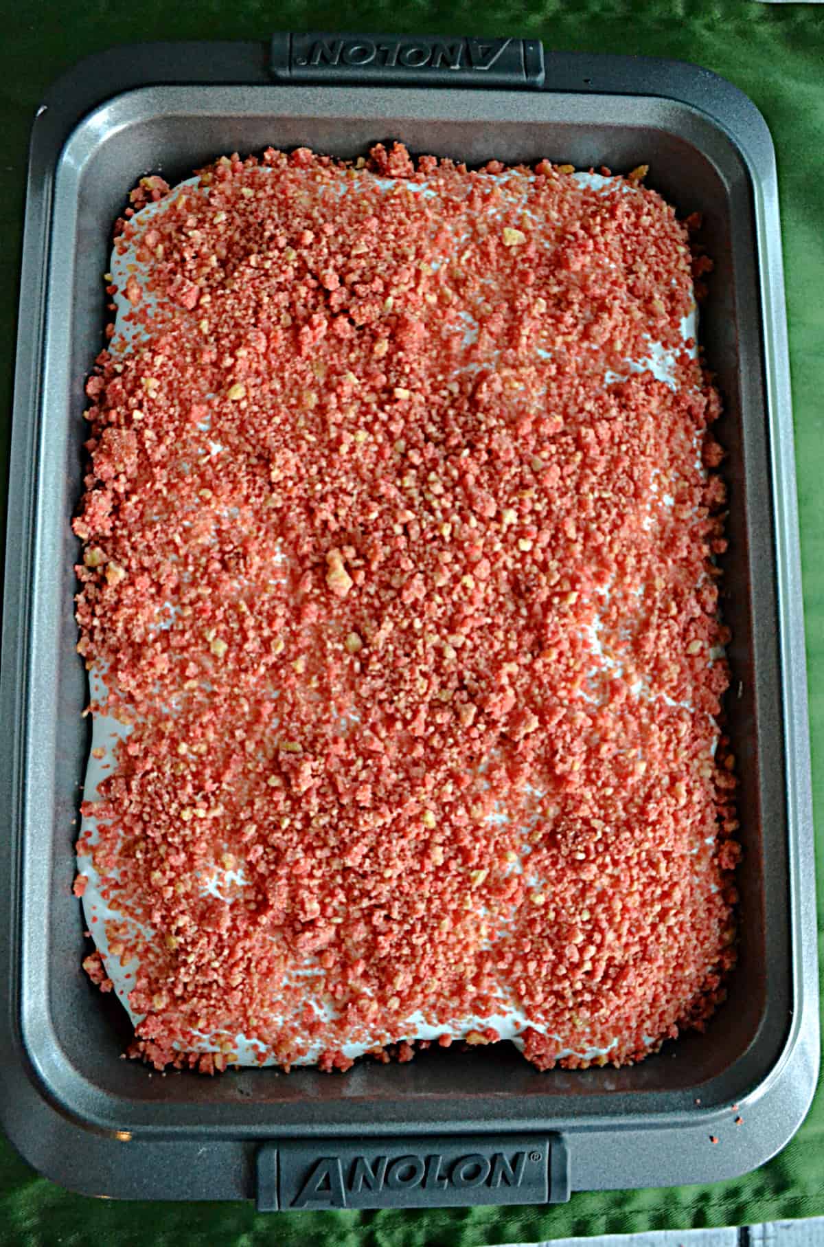 A cake with whipped frosting and pink strawberry scooter crunch topping.