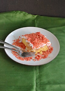 A plate with a slice of Strawberry Scooter Crunch Cake and 2 forks.