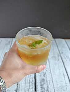 A hand holding a frosted glass of mint julep.