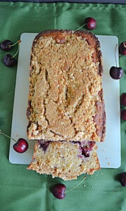 Cherry Bread with a slice cut off and cherries around it.