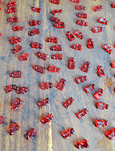 A cutting board with red gummy bears on it.