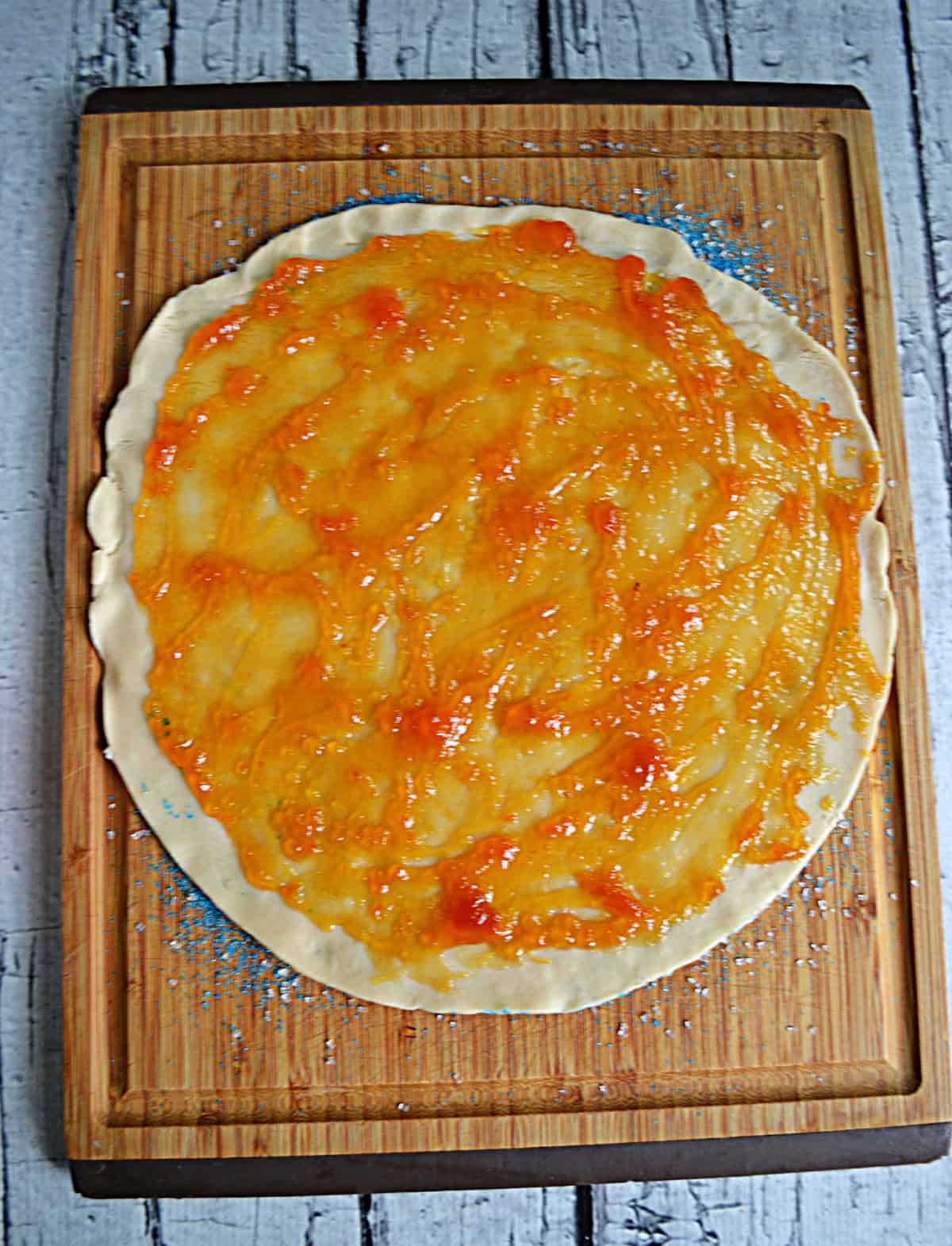 A pie crust with apricot jam spread on it. 
