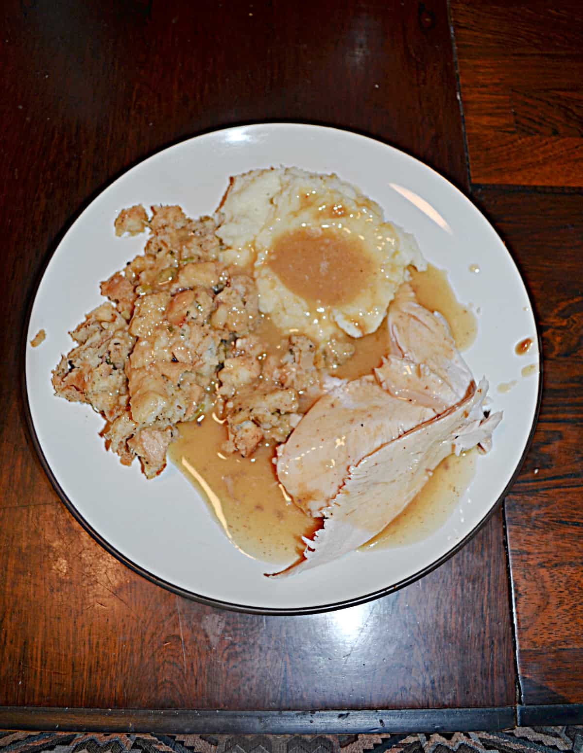 A plate with turkey, mashed potatoes, stuffing, and gravy on it.
