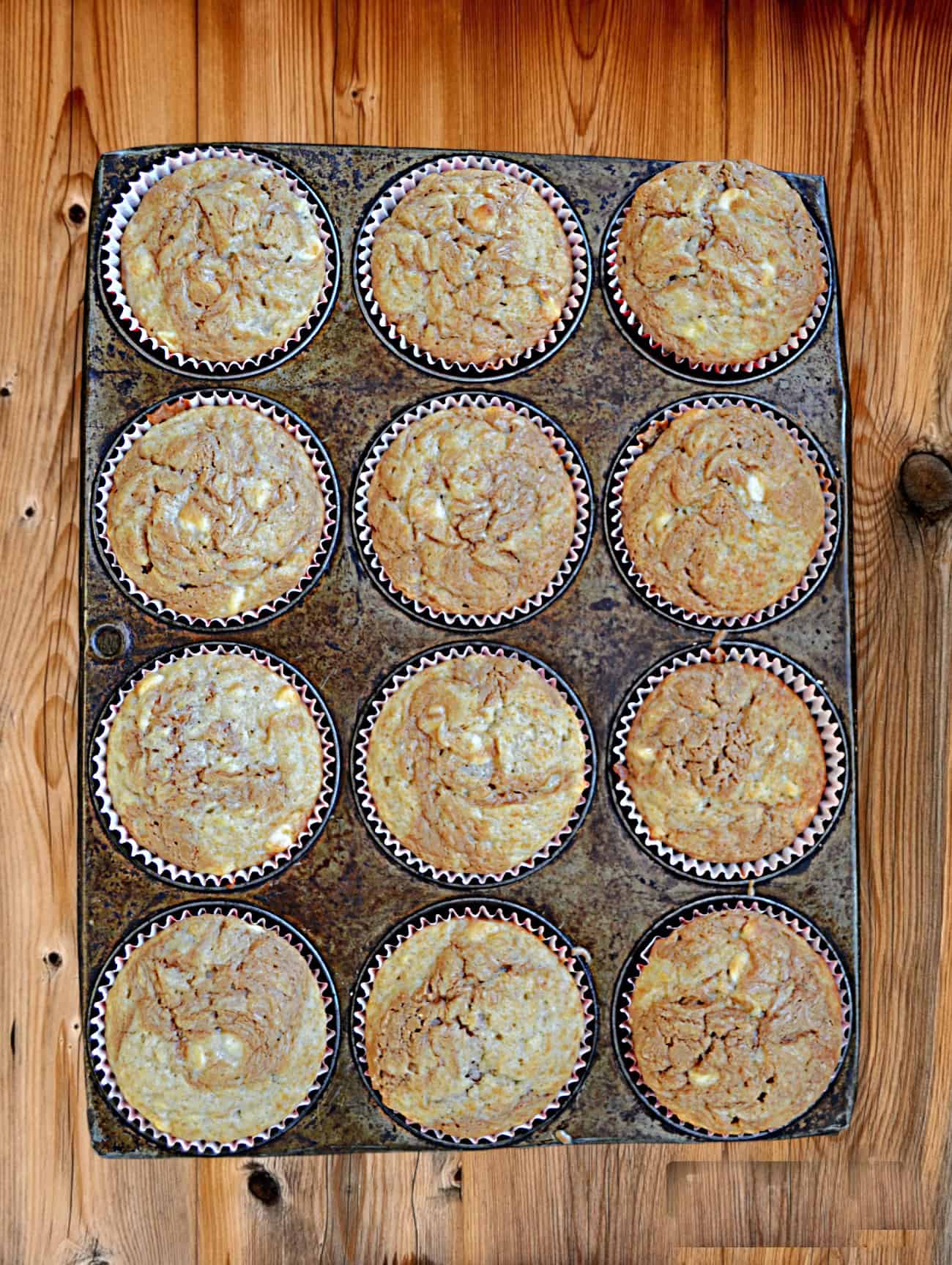 A muffin pan with 12 baked muffins. 