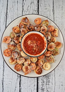 A plate of fried tortellini with a bowl of marinara in the middle.