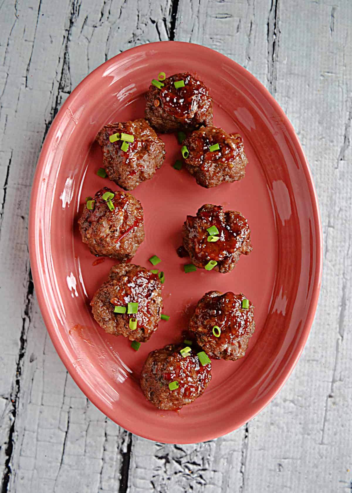A plate of Thai meatballs with green onions on top.