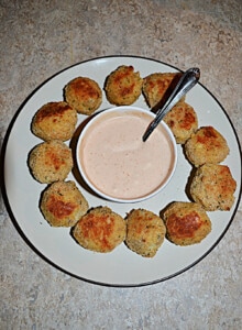 A plate of sauerkraut balls with dipping sauce in the middles.