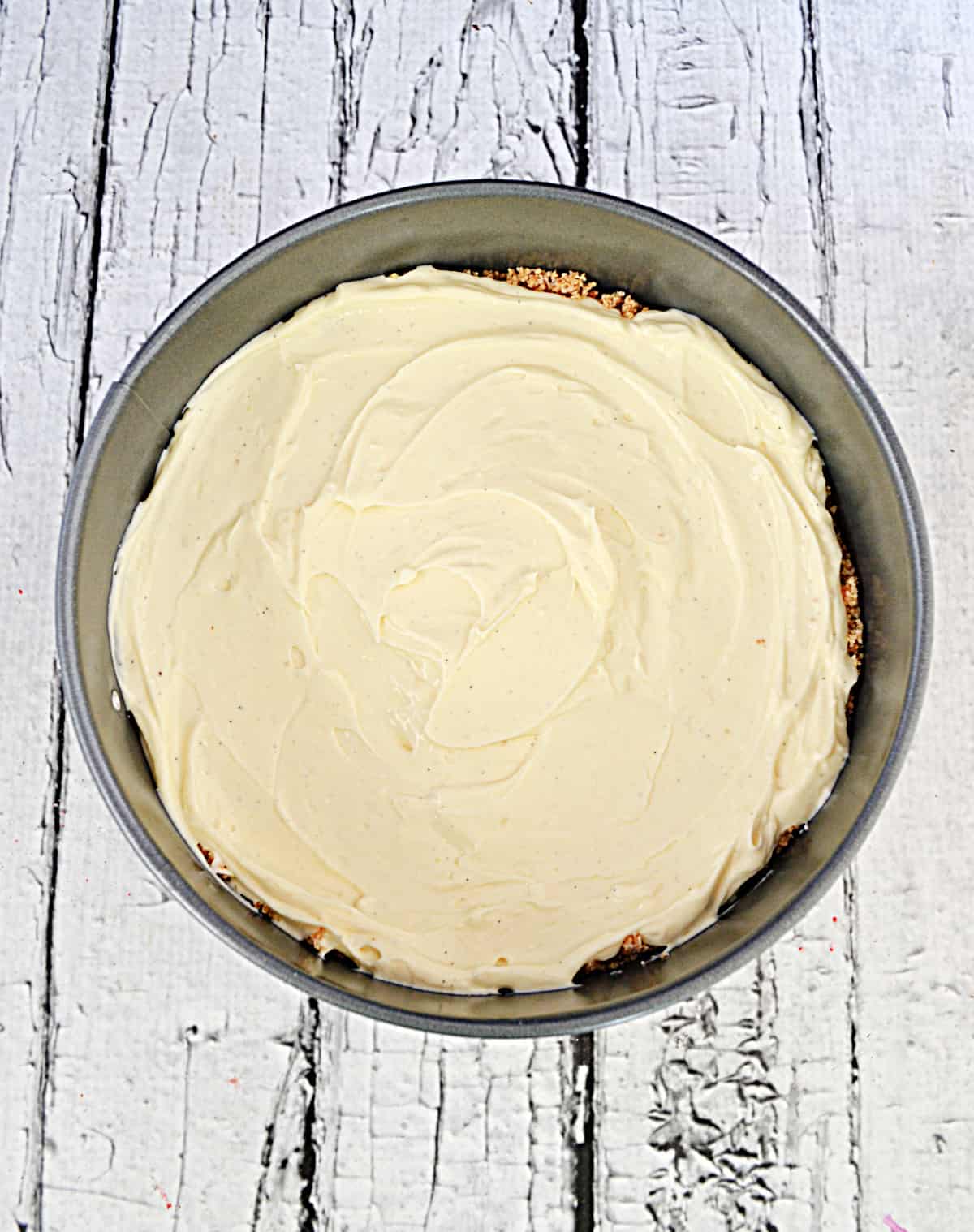 A vanilla bean cheesecake in a pan.