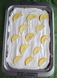 A cake with whipped frosting and lemon wedges on top.