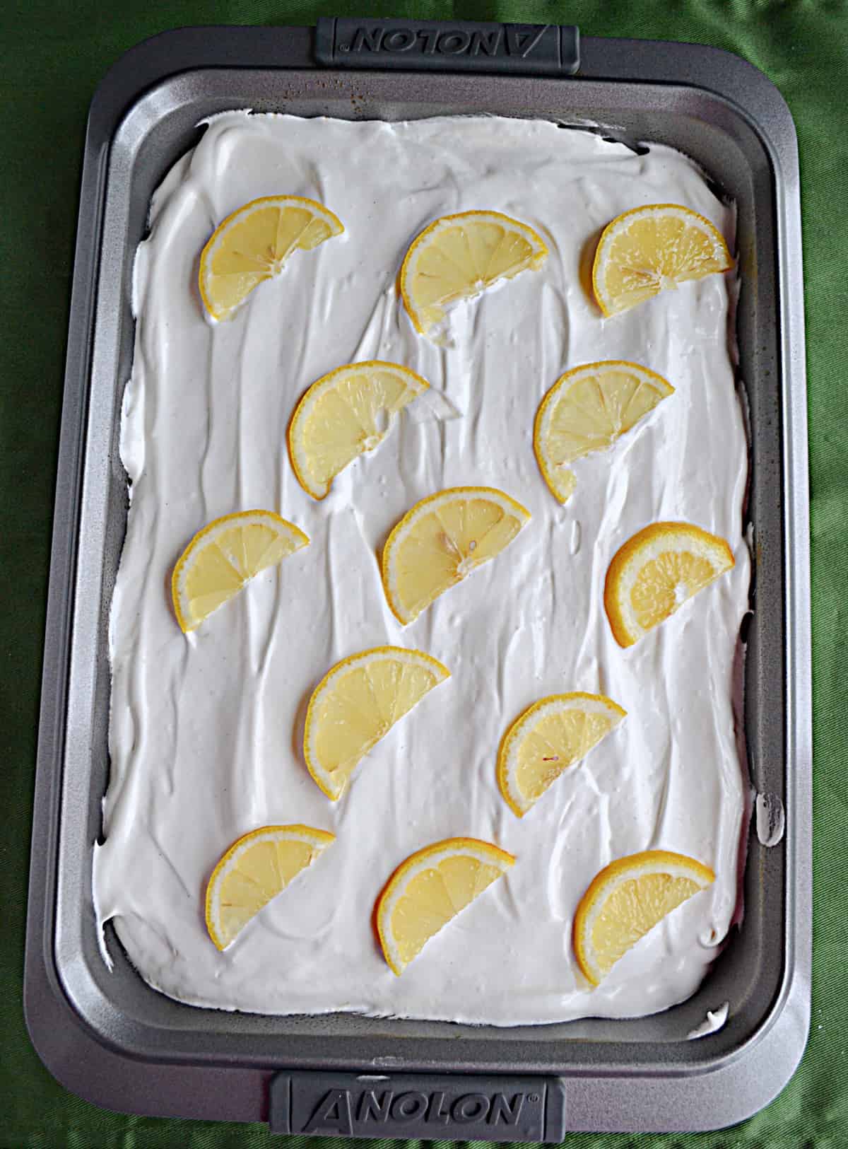 A cake with whipped frosting and lemon wedges on top.